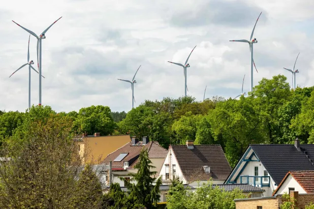 Conventional wind turbines are seen behind houses in Schipkau, eastern Germany on May 13, 2026. (Photo by Odd ANDERSEN / AFP) 
