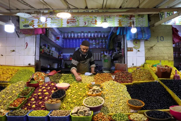 صاحب متجر يرتب الزيتون داخل سوق شعبية في الدار البيضاء (رويترز)