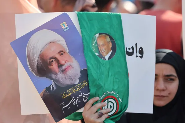 A woman holds pictures of Lebanese parliament Speaker Nabih Berri (R) and Hezbollah's leader Naim Qassem (L) while residents of the devastated southern Lebanese border villages protest against the destruction of their villages and being prevented from returning by order of the Israeli army, at Martyrs’ Square in central Beirut on April 30, 2026. (AFP)