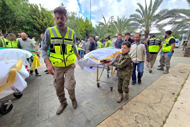 أشخاص يصلون برفقة جثامين ضحايا الغارة الإسرائيلية على قرية دير قانون النهر الجنوبية لبدء مراسم الدفن في منطقة صور بجنوب لبنان (أ.ف.ب)