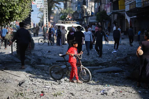 فتى فلسطيني يقف وسط حطام مبنى دمره قصف إسرائيلي في مخيم النصيرات بوسط قطاع غزة (أ.ف.ب)