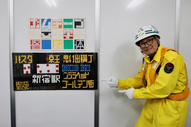 Shuetsu Sato, a security guard whose handmade duct-tape signs have gained widespread recognition, poses with duct-tape signs which he made at a security company office where he works, in Tokyo, Japan, May 1, 2026. (Reuters)