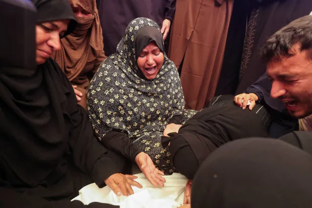
يبكون طفلة قُتلت بغارة إسرائيلية على خيام النازحين في خان يونس جنوب غزة أمس (رويترز)