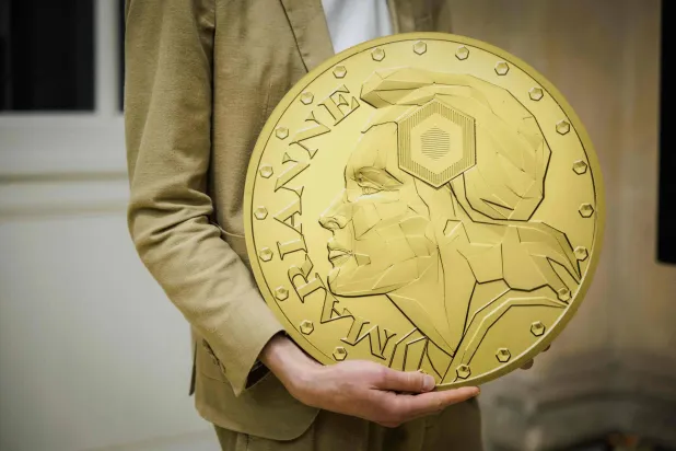 A worker holds a Marianne-Or gold coin bullion replica at La Monnaie de Paris in Paris on May 21, 2026. (Photo by SIMON WOHLFAHRT / AFP)