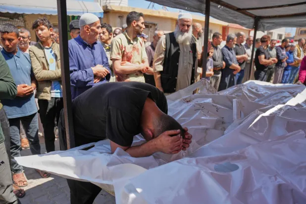رجل ينحني فوق جثث فلسطينيين قتلوا في غارة إسرائيلية على مخيم المغازي للاجئين وسط غزة الثلاثاء (أ.ب)