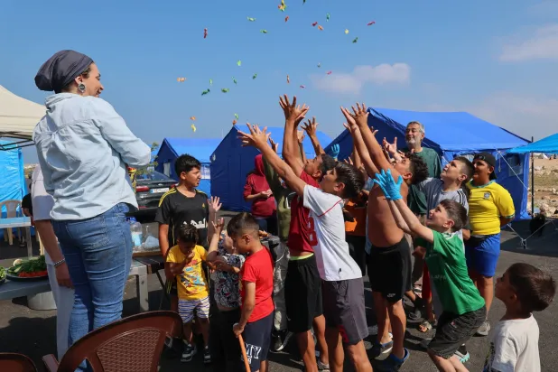 A woman tosses sweets to displaced children at a makeshift camp for displaced people at Beirut's waterfront during Eid al-Adha, the Feast of Sacrifice, in Beirut, Lebanon, 27 May 2026.   EPA/WAEL HAMZEH