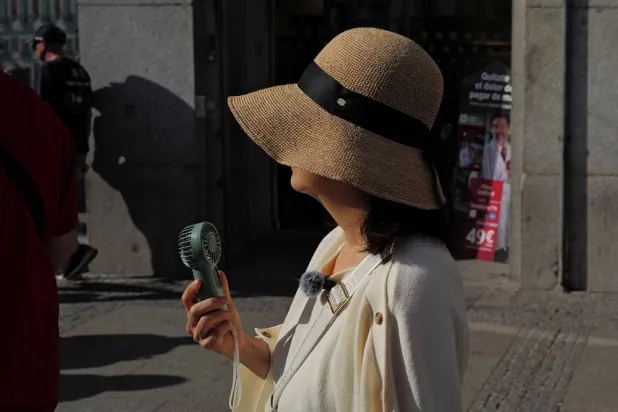  A woman uses a portable fan as she walks at Plaza Puerta del Sol during a spring heatwave in Madrid, Spain, May 27, 2026. (Reuters)