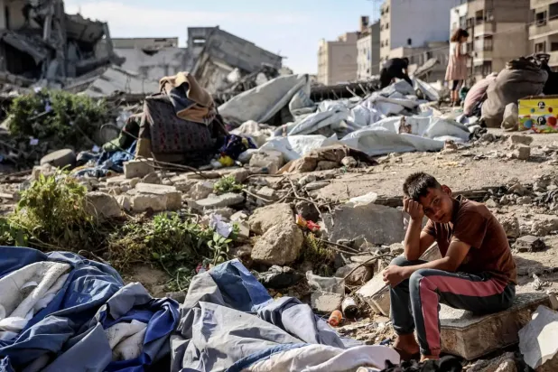 Filistinli bir çocuk, dün gece Gazze şehrinde 10 kişinin ölümüne neden olan İsrail hava saldırısının hedef aldığı noktada oturuyor (AFP)