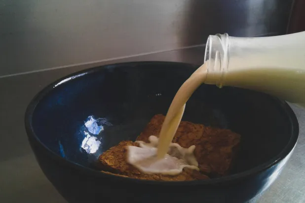 شخص يسكب الحليب في وعاء على حبوب الإفطار (بيكسلز)