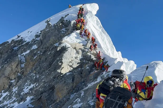 This photograph taken on May 20, 2026, shows mountaineers climbing a slope lined up during their ascent from the Hillary Step to summit Mount Everest in Nepal. (Furte Sherpa / AFP) 