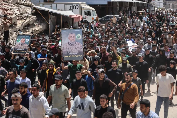 Mourners carry portraits of Ezzedine Al-Haddad, the slain chief of the Qassam Brigades -- the armed wing of Palestinian movement Hamas, who was killed in an overnight Israeli strike along with his daughter and wife, during their funeral in Gaza City on May 16, 2026. (AFP)