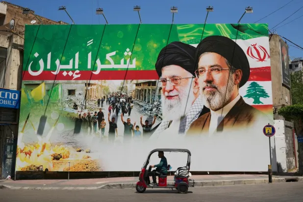 Hizbullah'ın karargahı sayılan Dahiye'de Ali Hamaney ve oğlu Mücteba Hamaney'in resmedildiği panoda "Teşekkürler İran" yazıyor (AP)