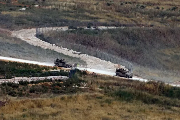 Yukarı Celile bölgesinden çekilen bu görüntüde, İsrail sınırına yakın güney Lübnan'daki bir yolda seyreden İsrail askeri araçları görülüyor (AFP)