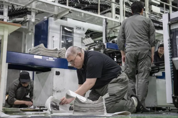 As the machine printed their work on newsprint paper, five technicians in uniform quickly flipped through the pages to check the quality. Yuichi YAMAZAKI / AFP
