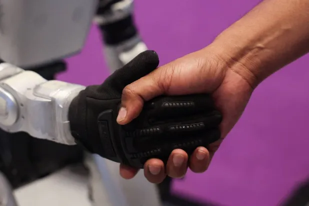 A man shakes the hand of a Chinese G1 humanoid robot made by Unitree Robotics at a conference in Mumbai, India, May 22, 2026. (Reuters)