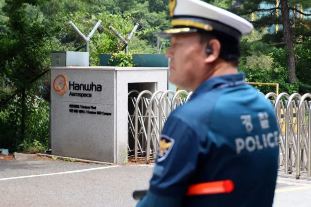 Daejeon'da patlamanın ardından alev alan fabrikanın ana giriş kapısının önünde bir polis memuru duruyor (Reuters)