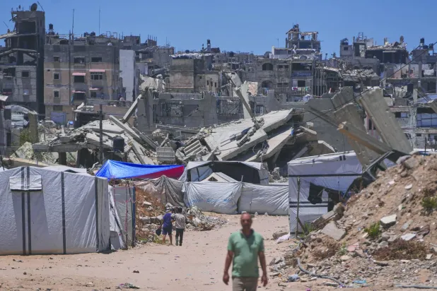 فلسطينيون يسيرون وسط مبانٍ دمَّرتها غارات إسرائيلية في جنوب غزة (أ.ب)