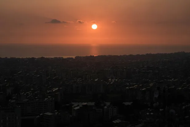 الشمس تغرب فوق الضاحية الجنوبية لبيروت في أعقاب تهديد إسرائيلي بضرب المنطقة (أ.ب)