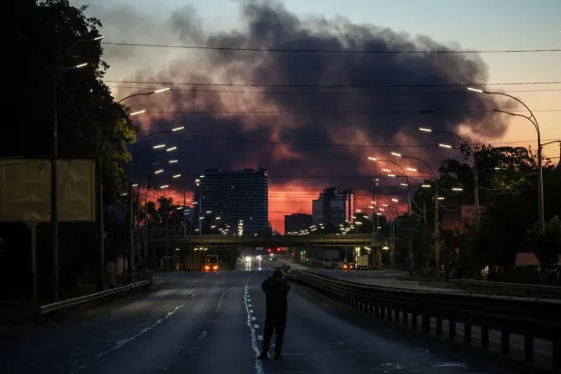  Rusya'nın Ukrayna'nın başkenti Kiev'e düzenlediği gece baskınının ardından yükselen dumanların fotoğrafını çeken bir kişi (Reuters)