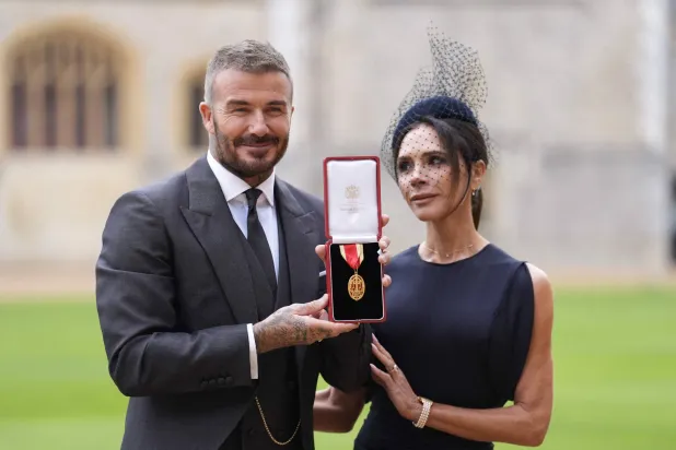 (FILES) Former England footballer David Beckham (L) poses next to his wife singer and fashion designer Victoria Beckham (R) with his medal after being appointed as a Knight Bachelor (Knighthood) for services to sport and charity at an investiture ceremony at Windsor Castle on November 4, 2025. (Photo by Andrew Matthews / POOL / AFP)