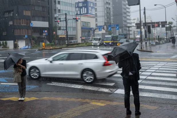 People commute in heavy rain brought by severe tropical storm Jangmi in Tokyo on June 3, 2026. (AFP)