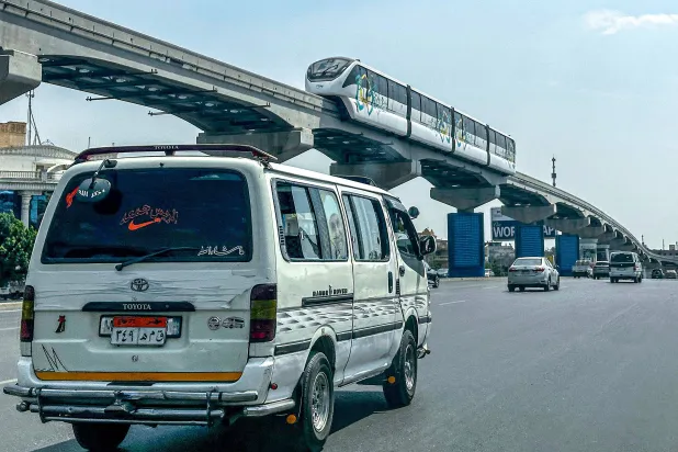 A minibus moves along a main road underneath new Cairo Monorail track as a train moves above in the Fifth Settlement, a neighborhood of the New Cairo suburb of Cairo, on May 22, 2026. (Photo by Khaled DESOUKI / AFP)