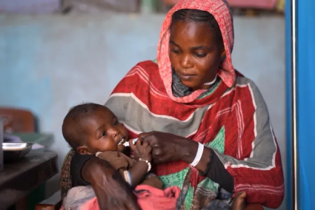 مواطنة سودانية تحاول إسكات جوع طفلها الرضيع (يونيسف)