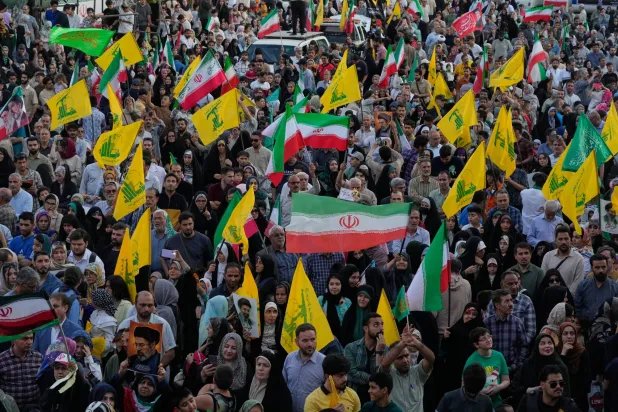 إيرانيون يحملون أعلام إيران و«حزب الله» في مسيرة في طهران (أ.ب)