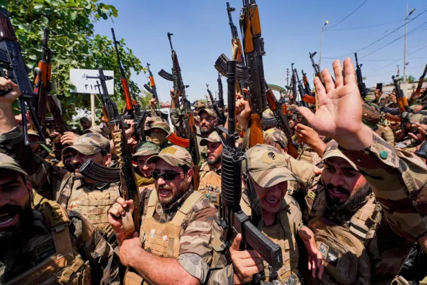 Members of the Saraya al-Salam faction cheer during a ceremony marking the start of the process of handing over their weapons to Iraqi state forces in Samarra, north of Baghdad, Iraq, Thursday, June 4, 2026. (AP)