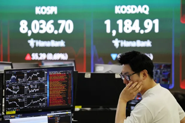 يعمل متداول فيما تعرض لوحة إلكترونية مؤشر«كوسبي» ومؤشر أسعار الأوراق المالية الكوري الآلي (كوسداك)، في غرفة تداول أحد البنوك في سيول (رويترز)