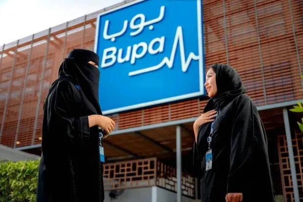 Two employees of Bupa Arabia pose beside one of the company’s office buildings. (Bupa Arabia website)
