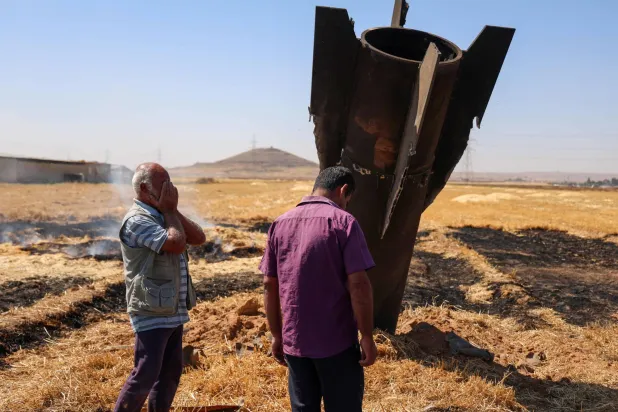 مزارعان سوريان بجانب صاروخ إيراني سقط بأرض زراعية في نجها بريف دمشق بعد أن اعترضته أنظمة الدفاع الجوي الإسرائيلية يوم 8 يونيو 2026 (أ.ف.ب)