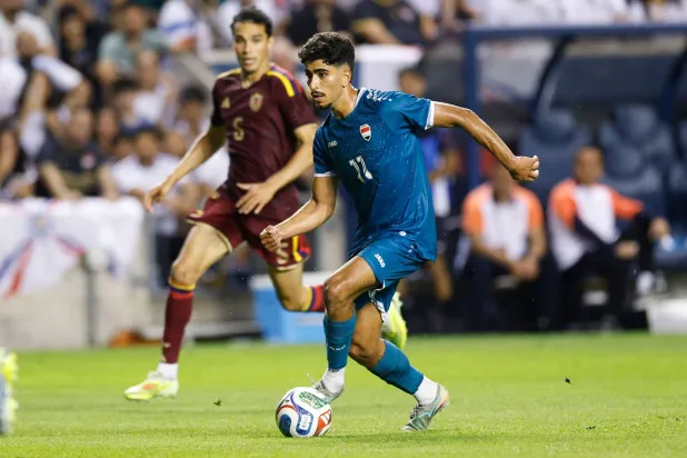  Iraq's forward #11 Ahmed Qasim runs with the ball past Venezuela's midfielder #05 Ted Quintero during the international friendly football match between Iraq and Venezuela at SeatGeek Stadium in Bridgeview, Illinois on June 9, 2026. (AFP)