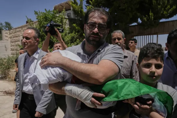 Fahd Ebu Heykel, geçen cuma günü İsrail askerleri tarafından öldürülen henüz bebek olan oğlu Sam'ın cesedini taşıyor (AP)