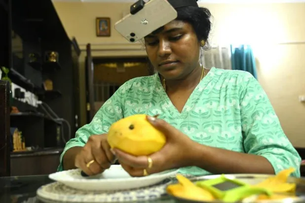Indian housewife Nagireddy Sriramyachandra wears a smartphone on her head as she records her actions through motion capture while slicing mangoes at her home in Chennai. R.Satish BABU / AFP
