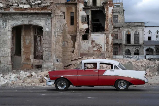An old car drives past debris from a demolished house occupying part of the seaside promenade in the Centro Habana neighborhood, in Havana on June 9, 2026. (Photo by Pablo PORCIUNCULA / AFP)
