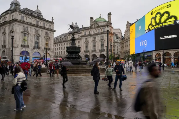 People hold umbrellas in Piccadilly Circus, in London, Thursday, June 11, 2026.(AP Photo/Alberto Pezzali)