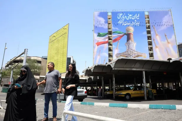 İranlılar, 11 Haziran 2026'da Tahran'da siyasi reklam panosunun önünden geçiyor (EPA)