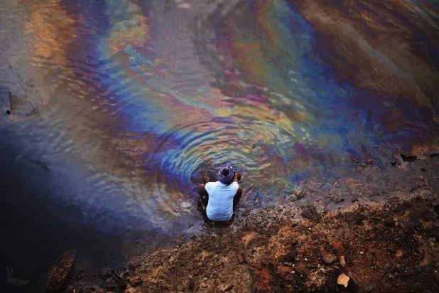 An Indian fisherman washes his hands in the waters of Ennore Creek covered with an oil spill after Cyclone Michaung, in Chennai, India, 11 December 2023. (EPA)