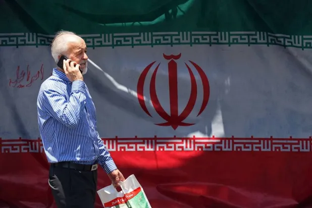 A man walks past Iran's national flag at the Vanak Square in Tehran on June 10, 2026. (AFP)
