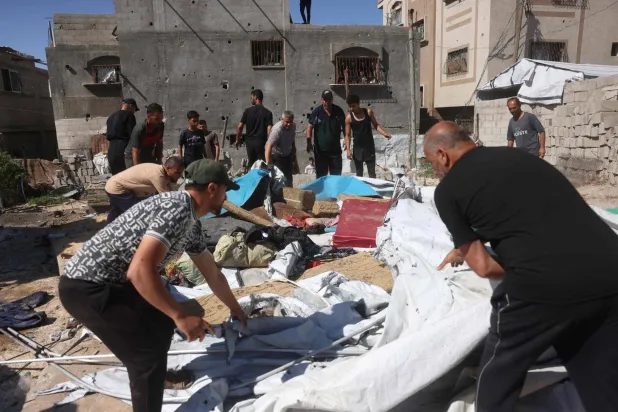 نازحون فلسطينيون يزيلون الرمال والحطام عقب غارة عسكرية إسرائيلية استهدفت خيامهم (أ.ف.ب)