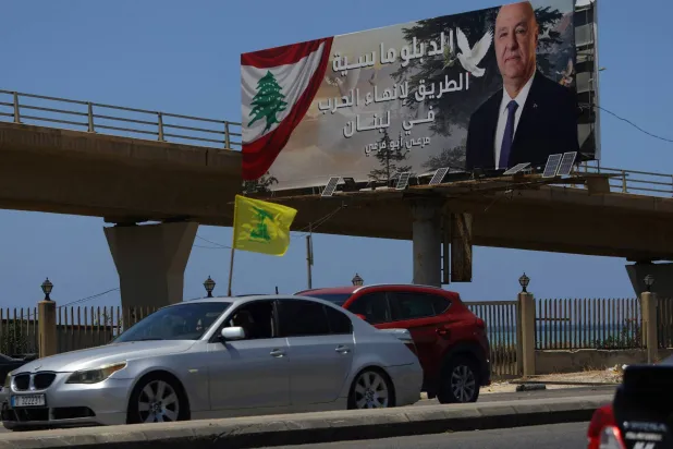 سيارة ترفع علم «حزب الله» في مدينة صيدا وبدت لوحة إعلانية للرئيس اللبناني جوزيف عون كُتب عليها: «الدبلوماسية هي السبيل لإنهاء الحرب في لبنان» (أ.ف.ب)