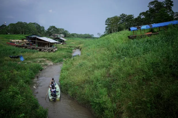 FILE - People maneuver by boat through the low water levels of a tributary that connects with the Amazon River, in Isla de la Fantasia, on the outskirts of Leticia, Colombia, Oct. 20, 2024. (AP Photo/Ivan Valencia, File)