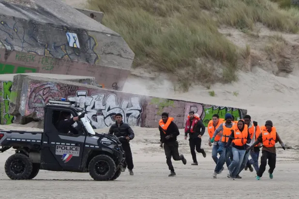 15 June 2026, France, Berck: People thought to be migrants, who were previously detained by the French police, run across the sand as they try to board a small boat off the coast of Berck, France, during an attempt to cross the English Channel. Photo: Gareth Fuller/PA Wire/dpa