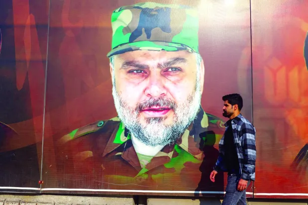  A man walks past a portrait of the influential cleric Moqtada al-Sadr wearing the military uniform of Saraya al-Salam, in a street in Baghdad, during the provincial council elections in Iraq, on Dec. 18, 2023. (AFP) 