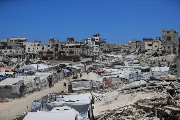 Palestinians make their way past the rubble of residential buildings destroyed during the Israeli offensive as displaced people shelter in tents, in Gaza City, June 15, 2026. (Reuters)