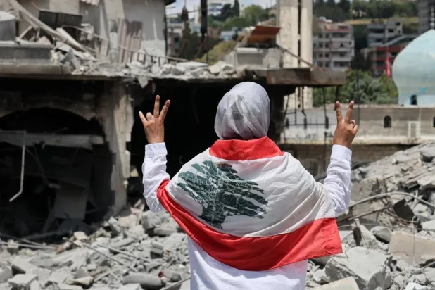 A woman flashes the victory sign next to destroyed buildings following Israeli strikes on the historic old market in the town of Nabatieh, southern Lebanon, 15 June 2026, after the announcement of a US-Iran mediated preliminary framework to end regional military hostilities and lift the naval blockade on the Strait of Hormuz. (EPA)