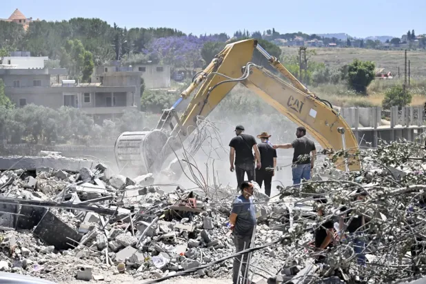 Lübnan'ın güneyinde yer alan Tulin köyünde iş makinesiyle yıkılmış bir binanın enkazı altındaki kayıpları arayan geri dönen köy sakinleri, 16 Haziran 2026'da. (EPA)