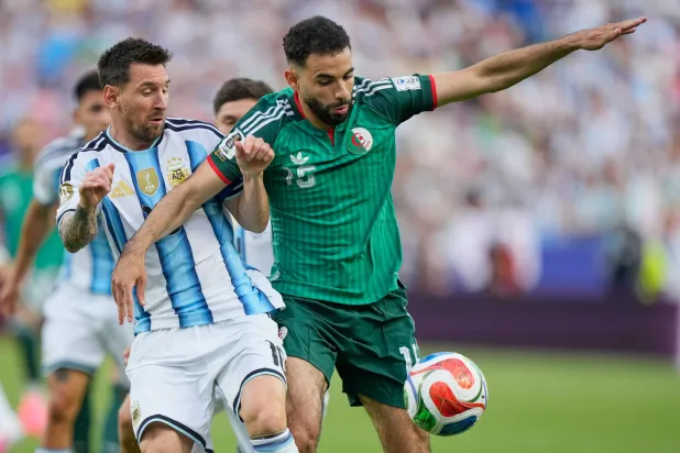 ميسي في صراع على الكرة مع آيت نوري لاعب الجزائر (أ.ب)