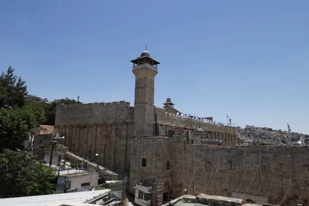 المسجد الإبراهيمي في البلدة القديمة بالخليل في الضفة الغربية المحتلة وعلى أحد جوانبه ترفع أعلام إسرائيلية يوم الأربعاء (رويترز)